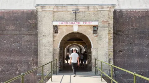 Getty Images Pintu masuk ke Landguard Fort. Seseorang berjalan ke pintu masuk gedung batu.