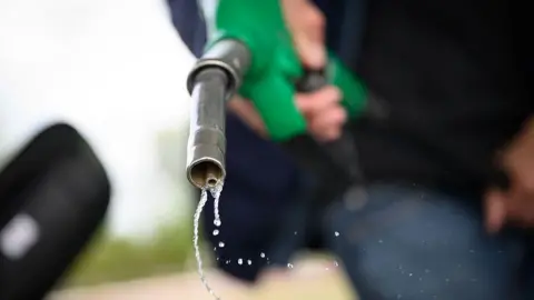 Petrol drips out of a fuel hose at a petrol station in Saint-Etienne-de-Montluc, western France, on 15 April, 2026.
