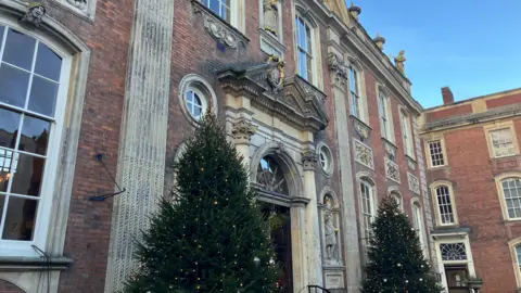 Two Christmas trees stand outside the main entrance to Worcester's Guildhall