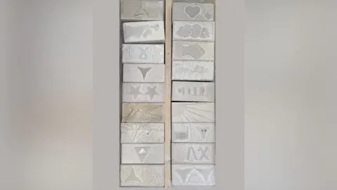 Rob MacDonald Two rows of 18 white rectangular cobbles which were made at the event. They have stars, hearts, flowers and sun rays carved on them.