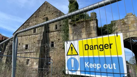 Derelict building with ivy growing up a chimney and a "Danger - Keep Out" sign