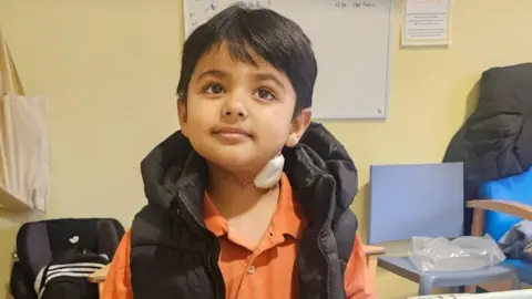 Family handout A close up image of a young boy, wearing a black gilet and an orange t-shirt. He has short black hair. 