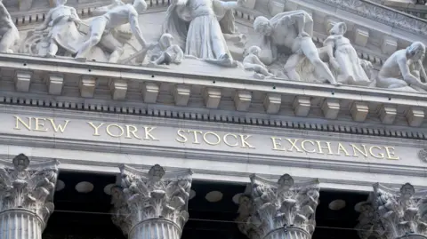 The exterior of the New York Stock Exchange, which features pillars and sculptures of a neoclassical style.