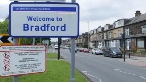 Getty Images A suburban street with a row of terraced houses. The street is the background to main pic of a 'welcome to Bradford' sign.