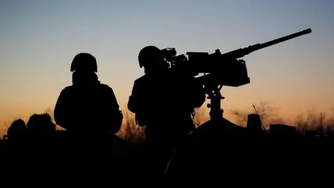 Anadolu via Getty Two soldiers in silhouette against a twilit sky