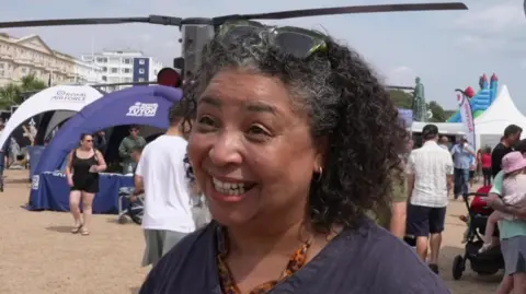 Jenny Williams smiles and wears blue in front of a helicopter