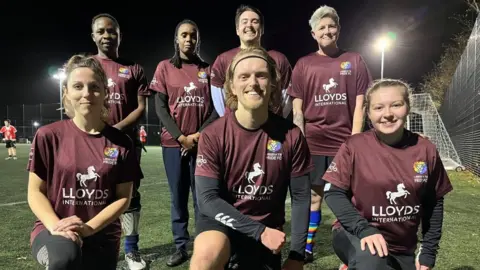 Liberates LGBTQ+ six a side team which has seven players in a squad photo taken on a floodlit pitch