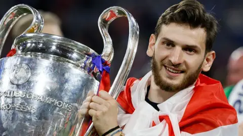 Khvicha Kvaratskhelia holding the Champions League trophy