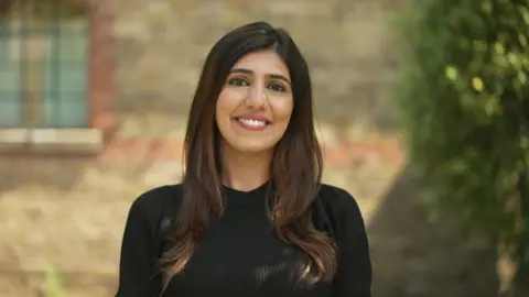 Lovina Shenoy in a black dress. She has brown hair. 