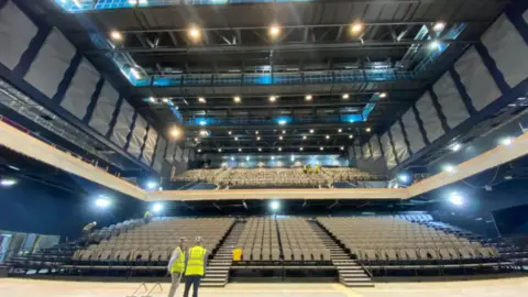 BBC Large indoor arena with thousands of seats and stage lights 