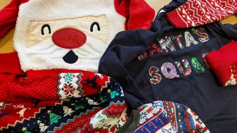 A collection of Christmas jumpers on a table.