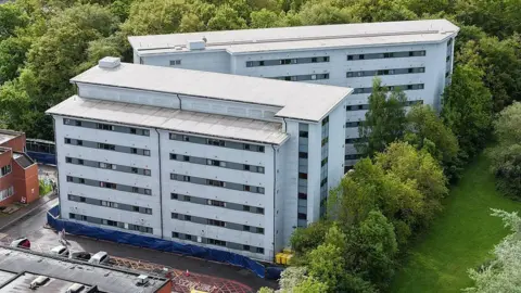 Getty Images An exterior, aerial shot of Arrowe Park hospital - showing two large white multi-storey buildings surrounded by a car park and trees.