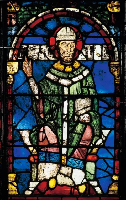 Getty Images A stained-glass window depicting a man wearing an archbishop's robes and hat in colours of green, pink, yellow and white, against a blue backdrop. 