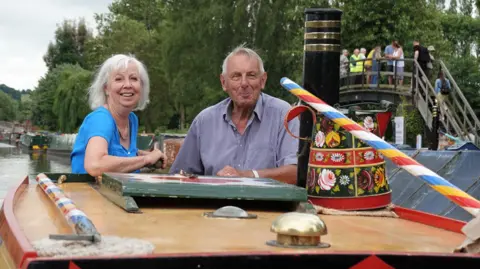 Braunston Marina Lady Sheila with light-coloured hair aboard a narrowboat with the owner