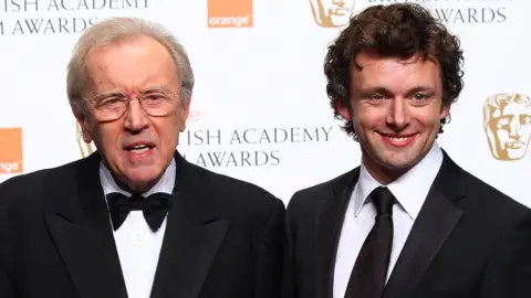 Getty Images Frost and Sheen both wears black suit jackets on the BAFTA red carpet. Frost with a bow tie, Sheen with a tie
