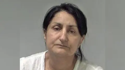 West Mercia Police  Police mugshot of Narinder Kaur, who is wearing a white top and has her hair tied back