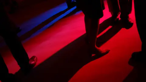 BBC People's legs on a darkly-lit dance floor.