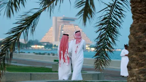 Getty Images Men walk along Doha corniche (file photo)