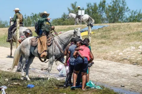 AFP A US Border Patrol agent on horseback tries to stop Haitian migrants from entering an encampment on the banks of the Rio Grande near the Acuna Del Rio International Bridge in Del Rio, Texas, on 19 September 2021