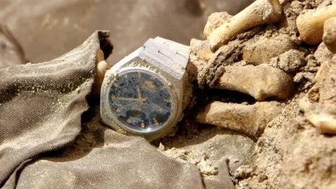 Getty Images A wrist watch is seen on a human skeleton and clothes from persons allegedly executed during the regime of former President Saddam Hussein