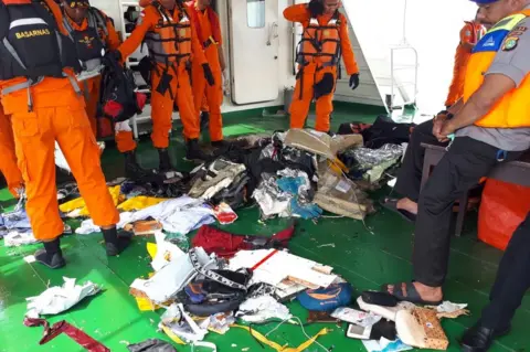 Search and rescue officials stand next to belongings salvaged from the sea