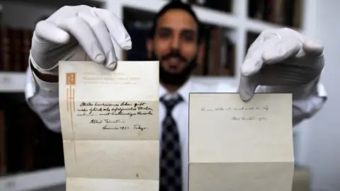 AFP Gal Winner, owner and manager of the Winner's auction house in Jerusalem, displays two notes written by Albert Einstein, in 1922, on hotel stationary from the Imperial Hotel in Tokyo (22 October 2017)