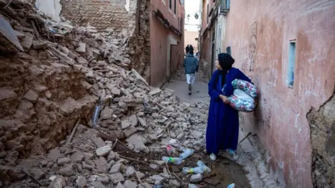 Getty Images A woman surveys the damage to a building in Marrakesh, reduced almost entirely to rubble