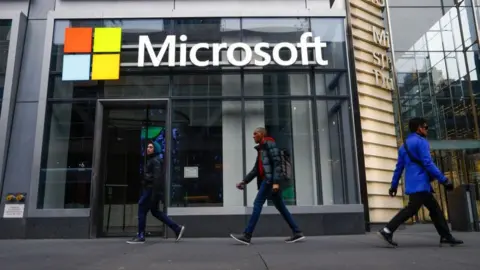 Getty Images People walk past a Microsoft office