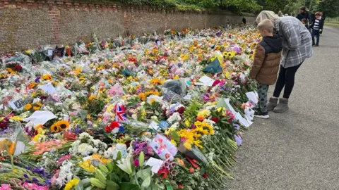Kate Scotter/BBC Woman and boy look at flowers
