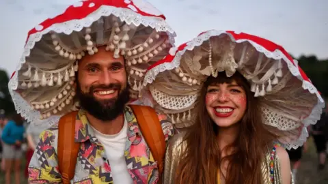 Getty Images A couple in fancy dress pose for a photograph during day one of Glastonbury Festival