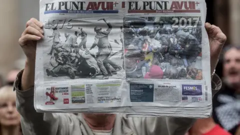 Getty Images A man holds up a newspaper showing images of police violence during protest in Barcelona against the violence that marred a referendum. 2 October, 2017 in Barcelona