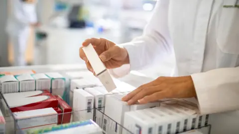 Marko Geber/Getty Images A pharmacist sorting through medicines