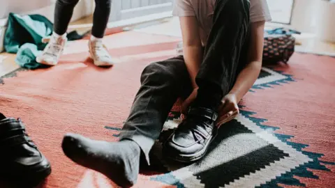 Getty Images Child putting on a pair of shoes