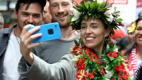 Reuters New Zealand"s Prime Minister Jacinda Ardern takes pictures with supporters during a campaign outing at Mangere Town Centre and market in Auckland, New Zealand, October 10, 2020.