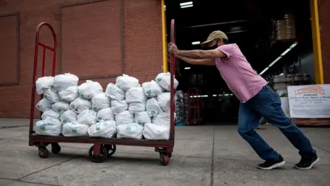 Getty Images Felix Pinzon, an unemployed construction worker pushes a cart of food delivery donations on May 19, 2020 in the Bronx borough of New York City.