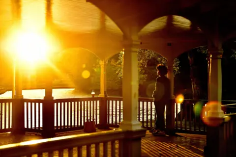 Clodagh Kilcoyne / Reuters A man watches the sunset from St Stephen's Green bandstand in Dublin, Ireland, on 19 October 2021