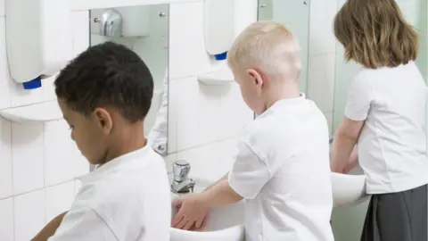 Getty Images Young children washing their hands at school