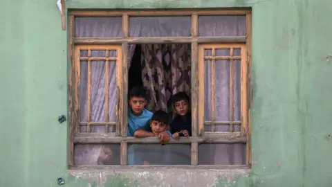 Getty Images Afghan children looking out of a window