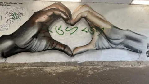 Emma Baugh/BBC A mural featuring two hands in a heart shape