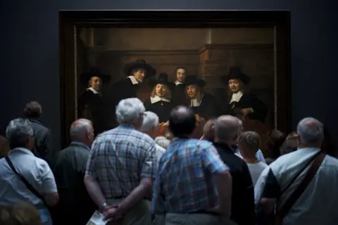 Julius Y. / National Geographic Museum visitors watching Rembrandt's painting Syndics of the Drapers' Guild