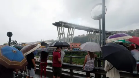 AFP People gather to watch the rescue operation after a section of a giant motorway bridge collapsed, on August 14, 2018 in Genoa