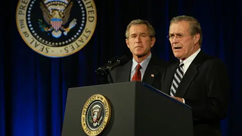 Getty Images Rumsfeld and George Bush at podium with presidential seal, in 2002 image