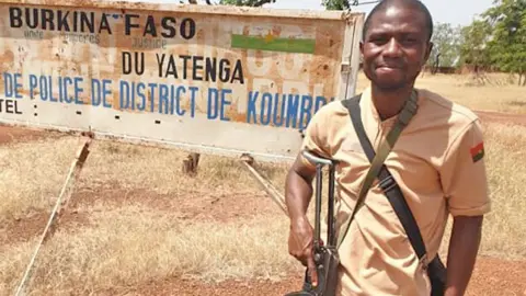 Dr Arouna Louré holding a gun during his three-month army deployment in Burkina Faso