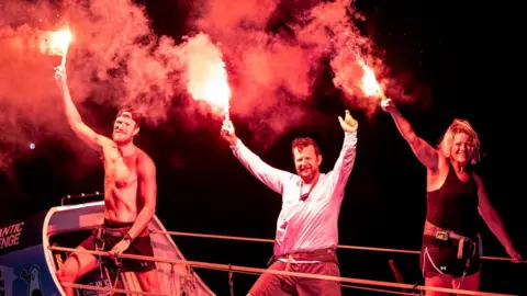 Raring to Row Rowers from team Ready to Row holding flares at the finish line in Antigua