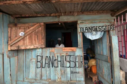 AFP A man is seen inside a wooden structure that has signs saying "blanchisserie", the French word for laundry, daubed in paint on the outside in Abidjan, Ivory Coast - Tuesday 19 February 2019