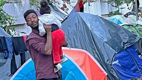 A man holding a child outside tents in Tunisia