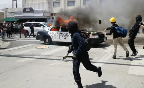 Getty Images An LAPD vehicle burns after being set alight by protestors during demonstrations following the death of George Floyd, in Los Angeles, California, 30 May 2020