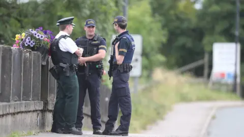 Niall Carson/PA PSNI and the Garda officers stand exactly on the border in Belleek, County Fermanagh, ahead of Theresa May's visit