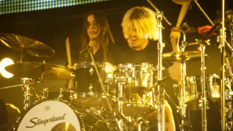 Redferns / Getty Images Alanis Morissette performs on stage with drummer Taylor Hawkins, circa 1995.