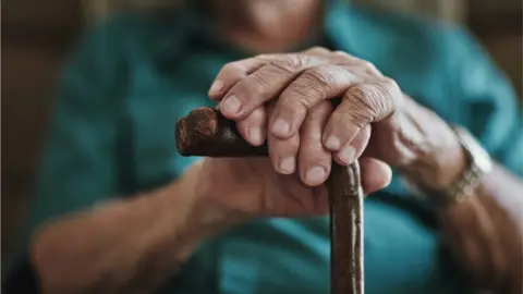 Getty/PeopleImages hands on walking stick